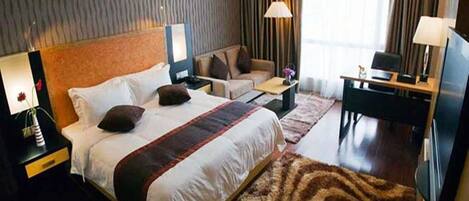 Ein Hotelzimmer mit einem großen Bett, einer Couch, einem Schreibtisch und einem Fernseher.