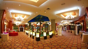 A spacious lobby with a patterned carpet, multiple chandeliers, and a central decorative area with plants and lighting. - Meritz Hotel (Miri)