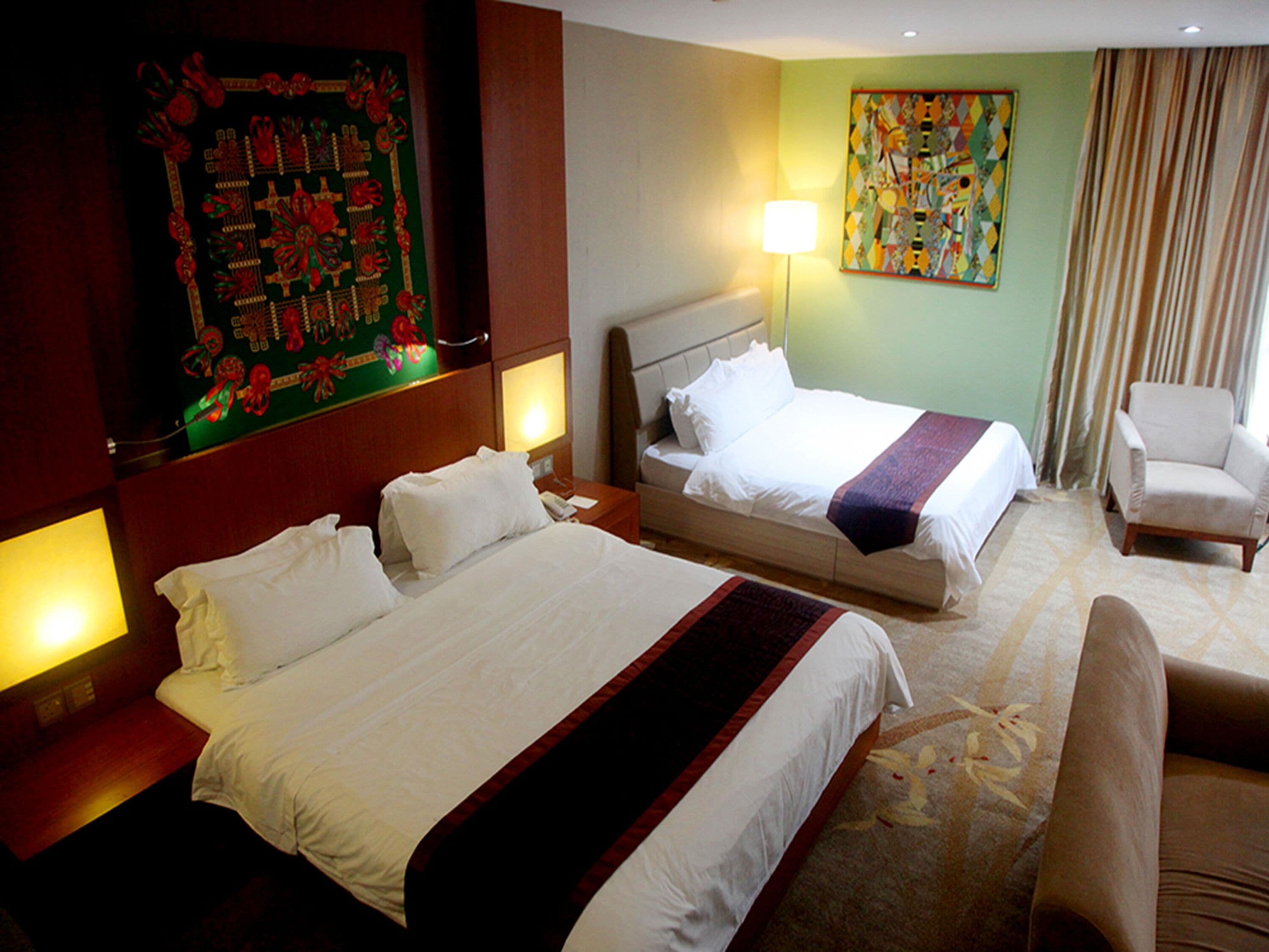A hotel room with two beds, a chair, and a painting on the wall.
