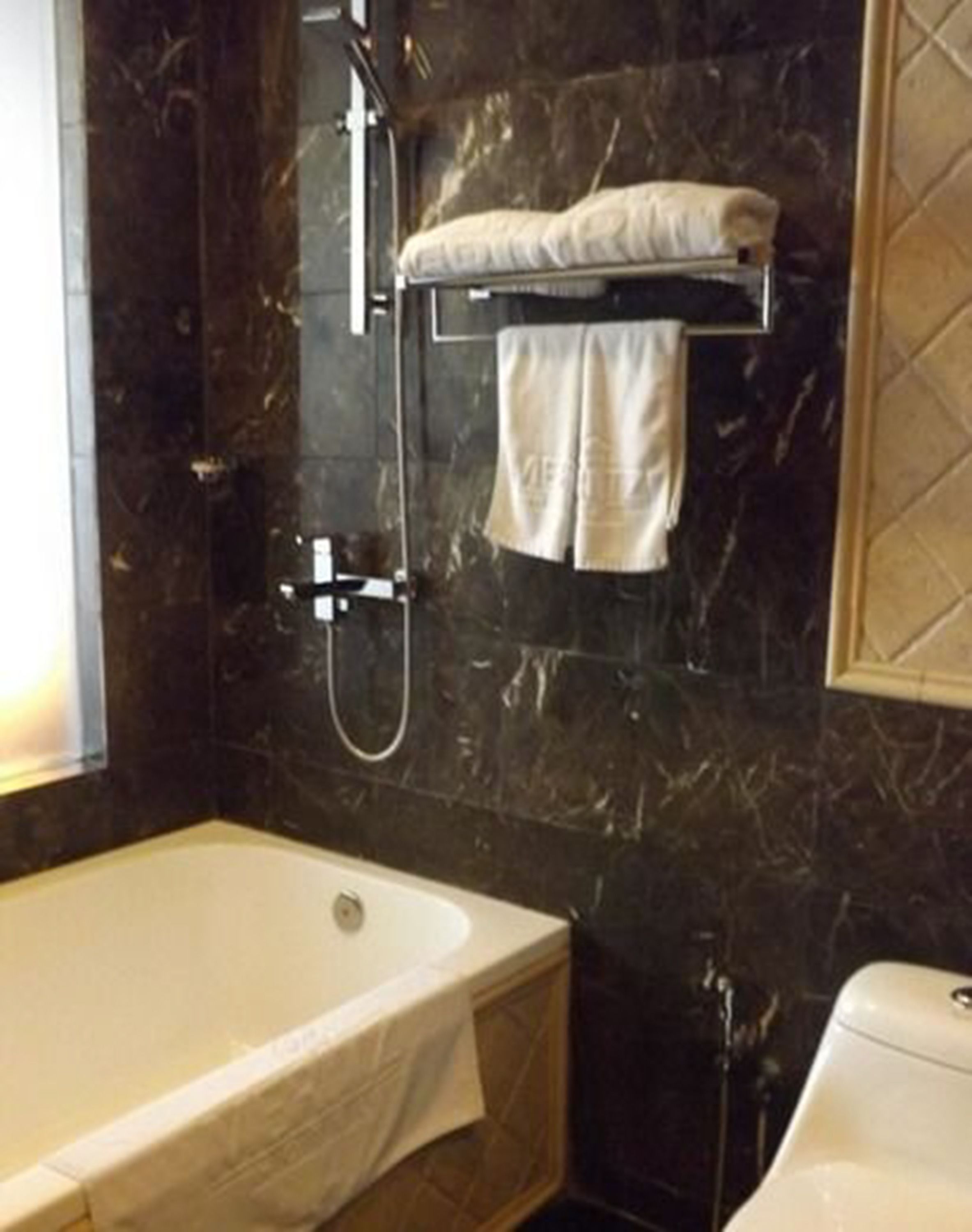 Un baño con bañera, ducha y un perchero para toallas.