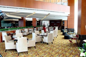 A spacious hotel lobby with multiple dining areas, a central atrium, and a view of the kitchen area. - Meritz Hotel (Miri)