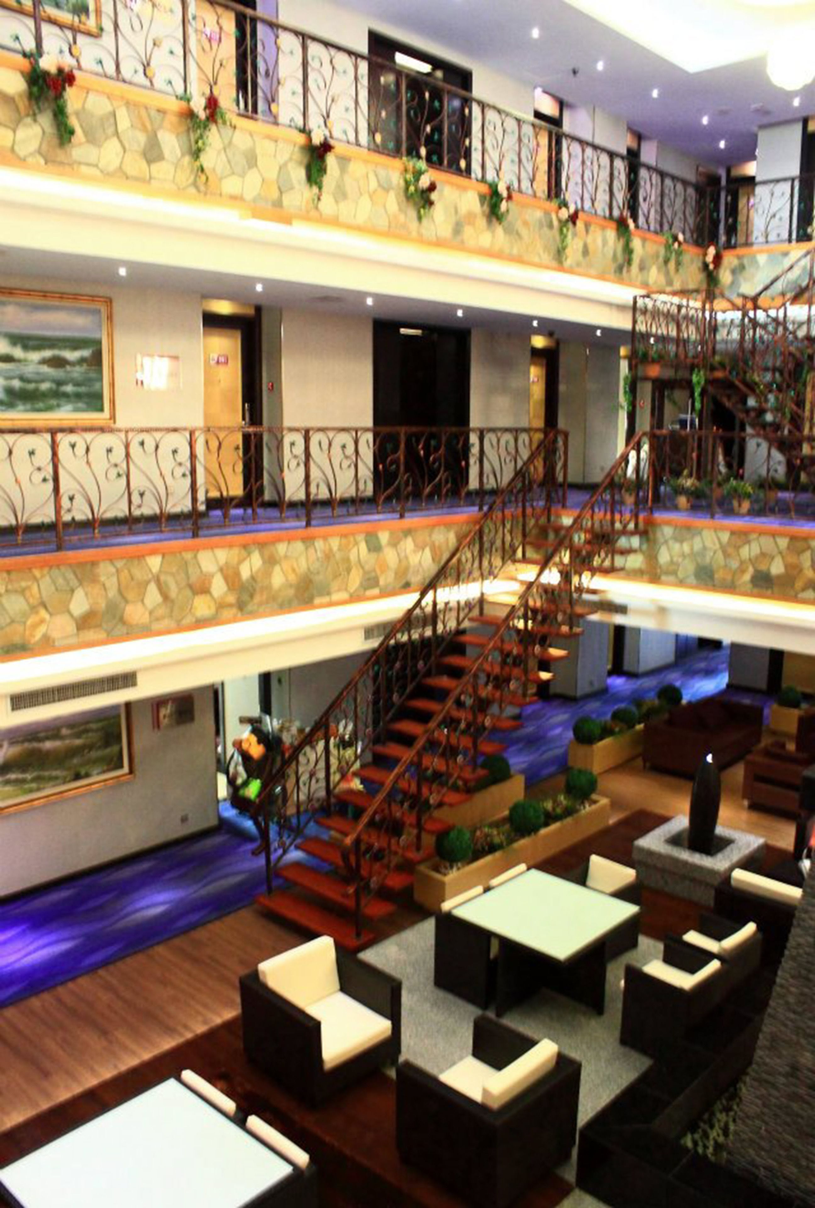 Een hotelentree met meerdere niveaus, een trap, zithoeken en uitzicht op de oceaan.