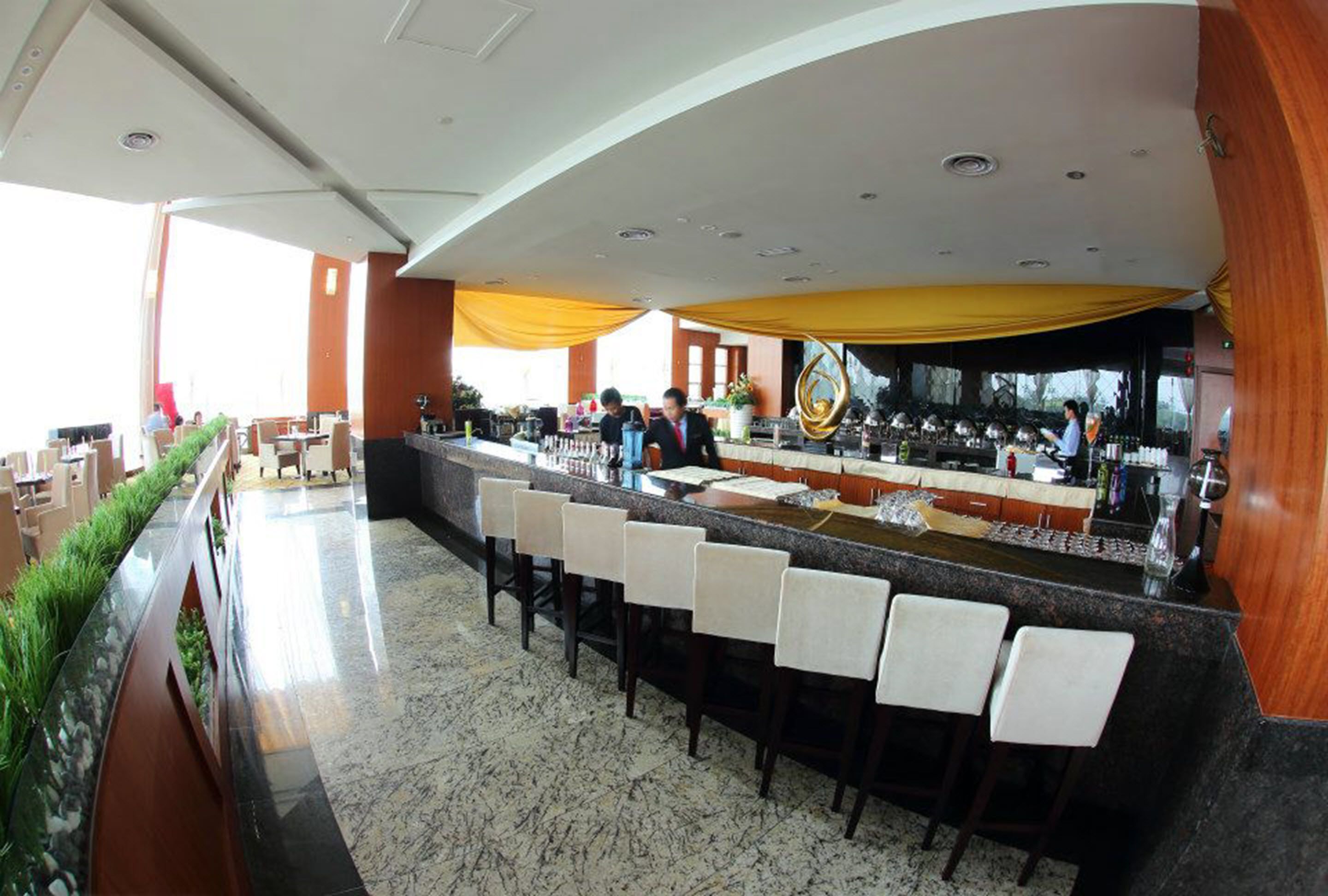 A modern bar area with a long counter and multiple bar stools.