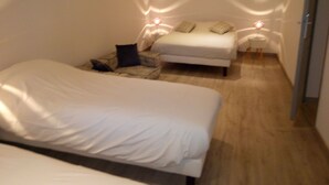A bedroom with two beds, a small seating area, and bedside lamps. - Hotel Central (Carcassonne)