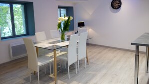 A modern dining area with a glass table, white chairs, and a vase of flowers. - Hotel Central (Carcassonne)
