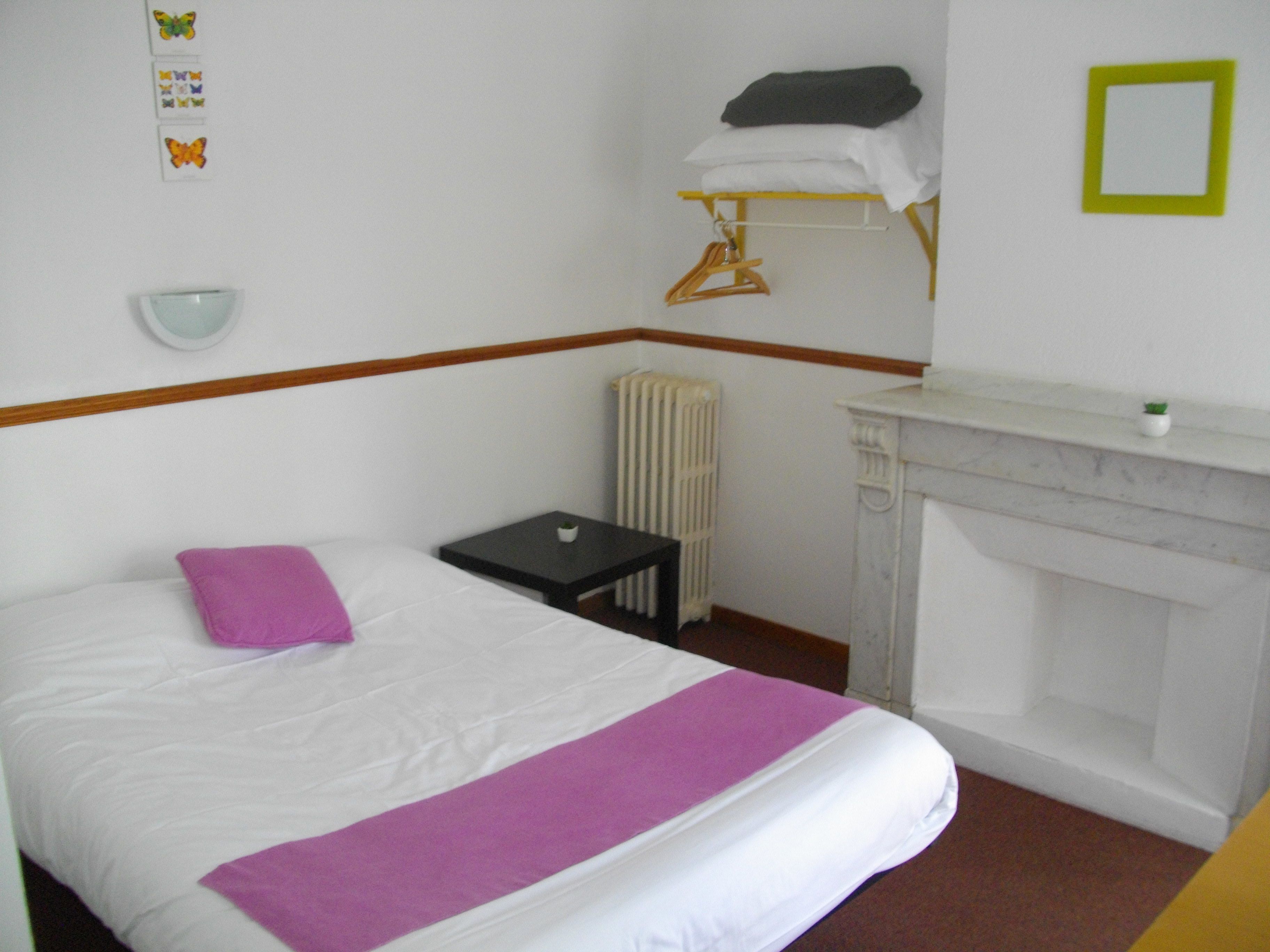 Una habitación de hotel con una cama, una mesita, un radiador y una chimenea.