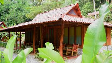 Une maison en bois avec un toit en tuiles, entourée d’une végétation luxuriante.
