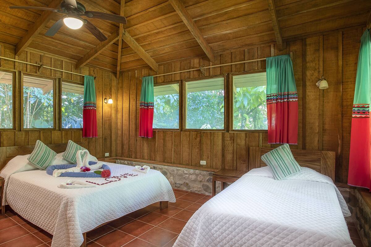 A wooden cabin with two beds, each with a pillow and a small bedside table.