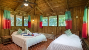 Uma cabana de madeira com duas camas, cada uma com travesseiro e uma pequena mesa de cabeceira.