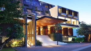 A modern building with a prominent entrance, a staircase leading to the main entrance, and a well-lit outdoor area with plants. - Four Points by Sheraton Bali Seminyak (Keroboken Kelod)