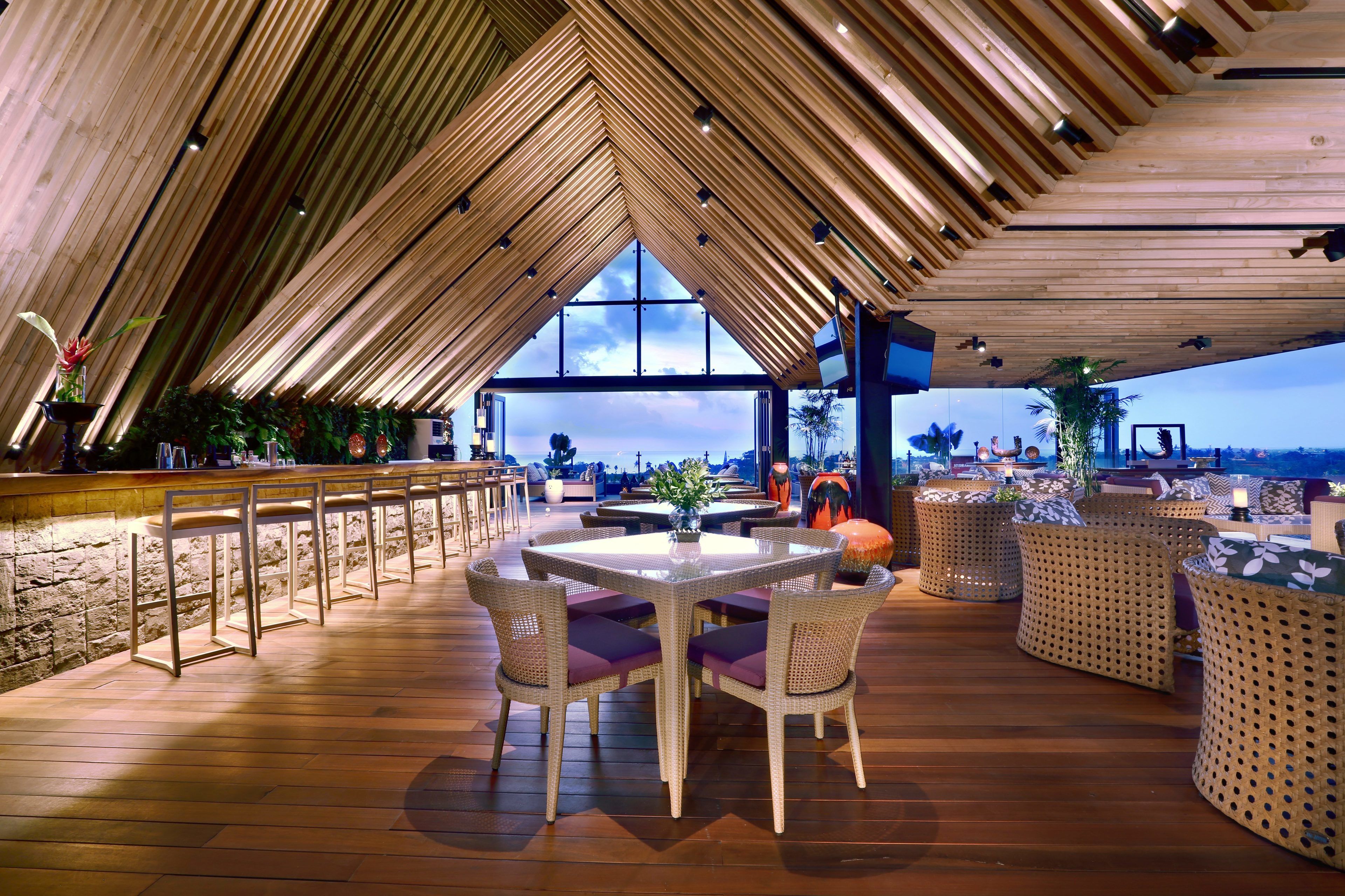 A spacious outdoor dining area with a high ceiling and a view of the landscape.