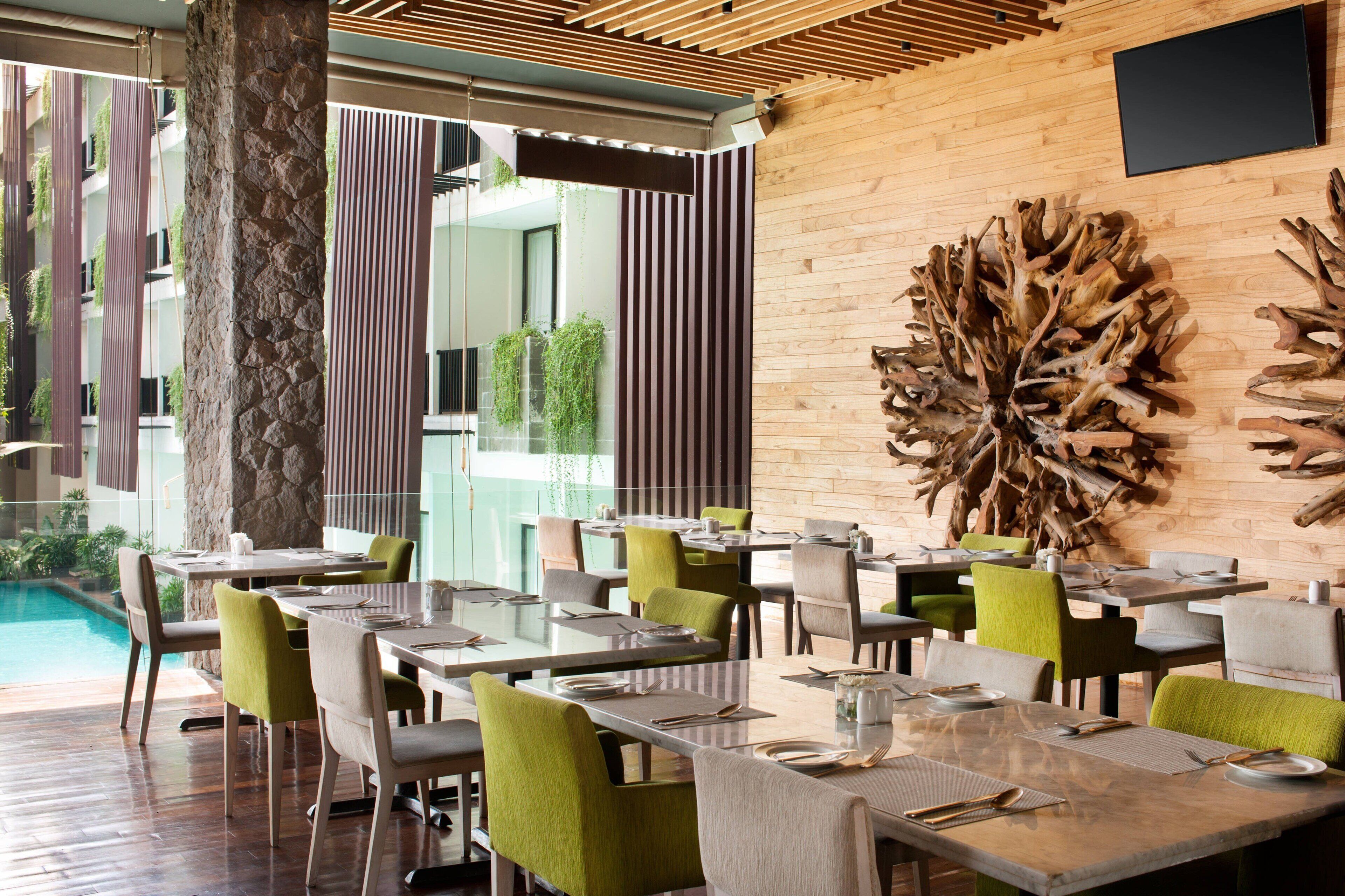 Un restaurant avec une terrasse, des tables en bois et des chaises vertes.