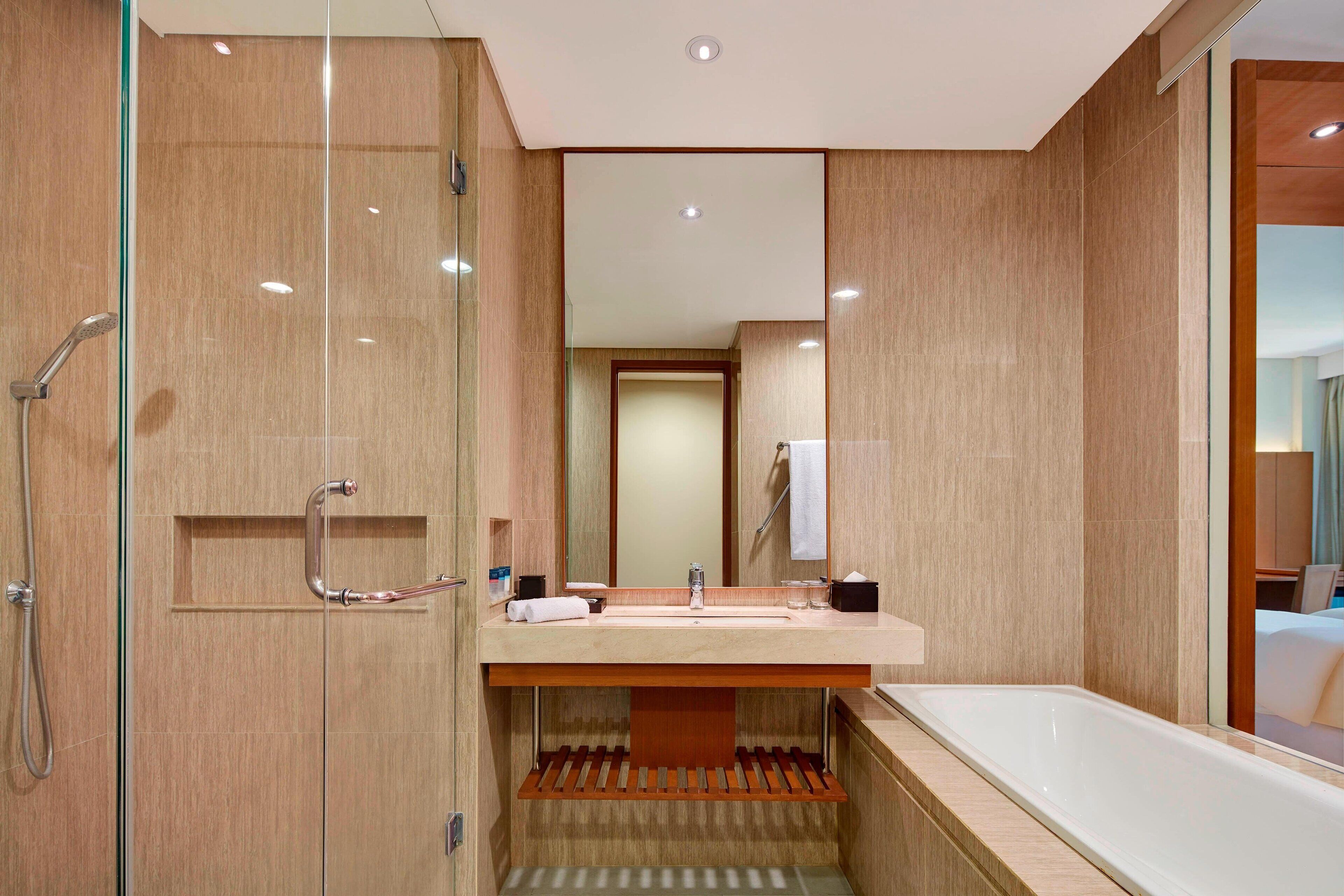 Une salle de bain moderne avec une douche à parois de verre, un lavabo avec un miroir et une baignoire.