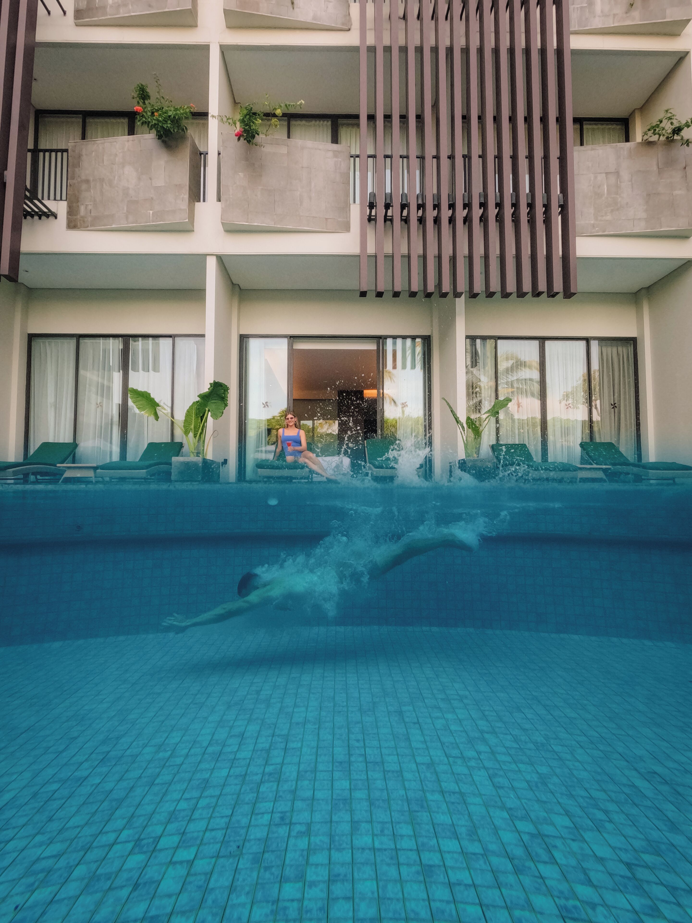 A hotel with a swimming pool, outdoor seating, and a modern architectural design.