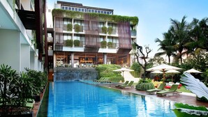 A hotel with a swimming pool, outdoor seating, and greenery. - Four Points by Sheraton Bali Seminyak (Keroboken Kelod)