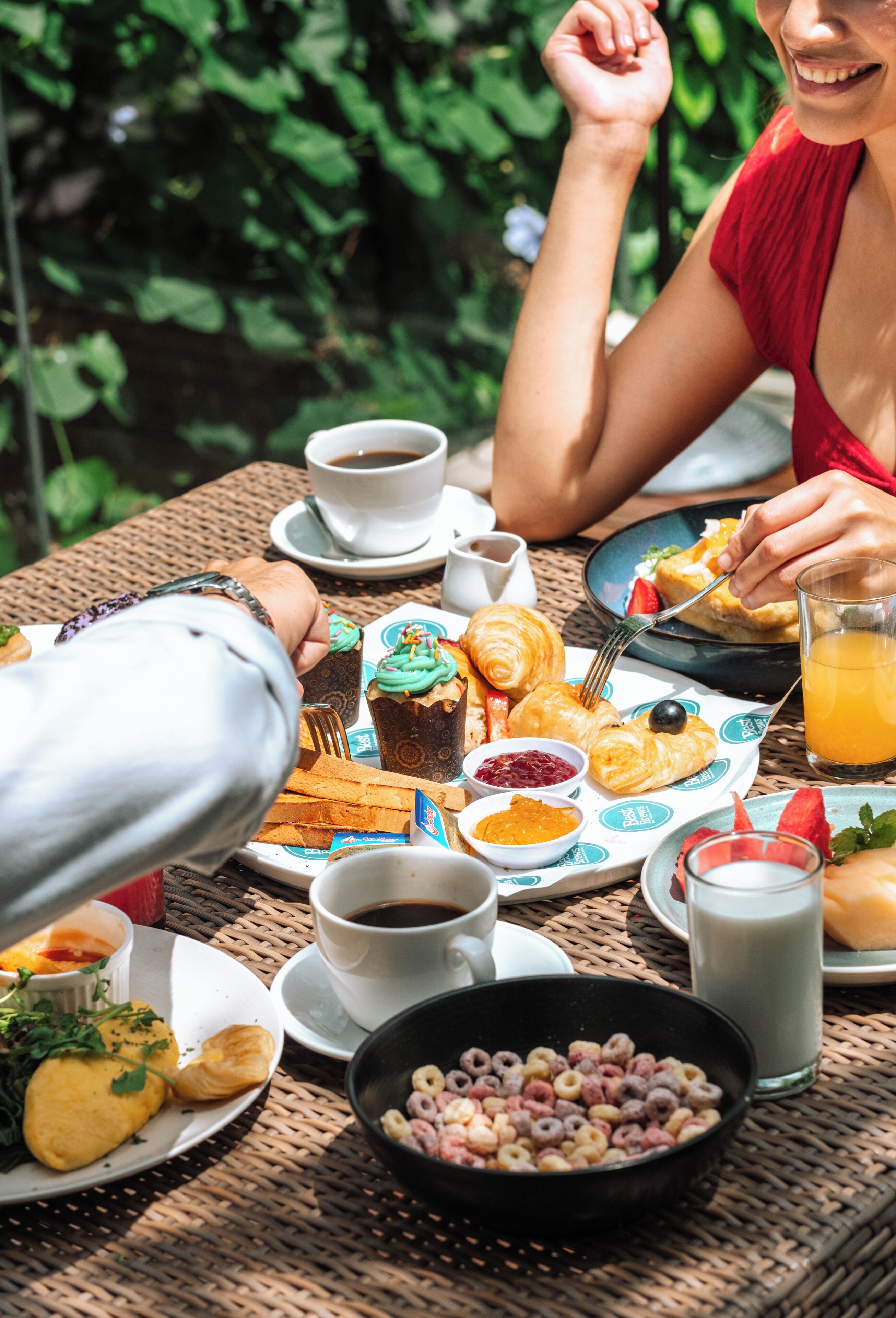 A wicker table with breakfast items including croissants, cereal, and coffee.