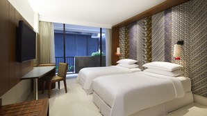 A hotel room with a large bed, a desk, a chair, a TV, and a balcony with a view. - Four Points by Sheraton Bali Seminyak (Keroboken Kelod)