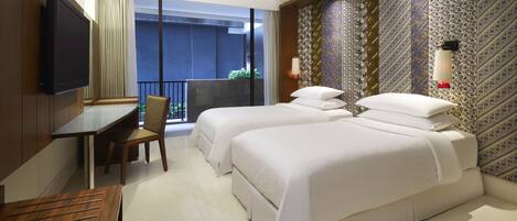 A hotel room with a large bed, a desk, a chair, a TV, and a balcony with a view.