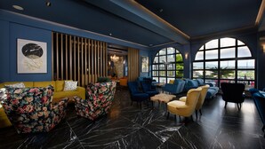 A modern lounge area with a yellow sofa, floral armchairs, and blue sofas. - The Royal Hotel (Corfu)