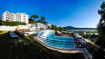 Un resort con una gran piscina, tumbonas y vistas al mar.