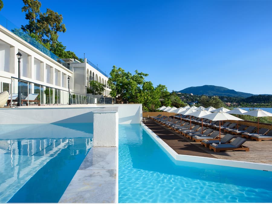 Una piscina al aire libre, sombrillas, sillones reclinables de piscina