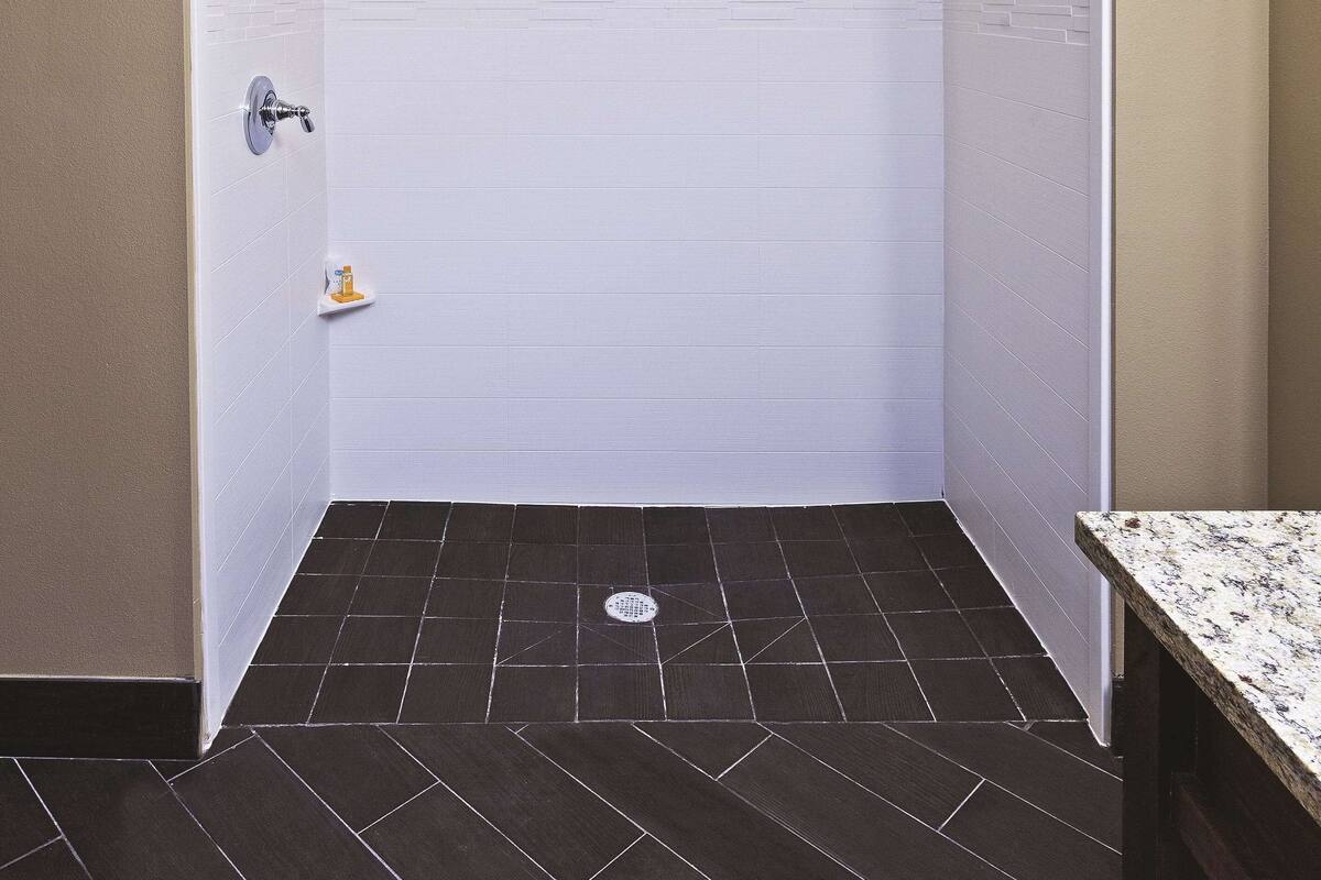 A small, narrow bathroom with white tiled walls and a dark tiled floor.