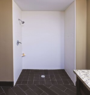Un baño pequeño y estrecho con paredes de azulejos blancos y piso de azulejos oscuros.