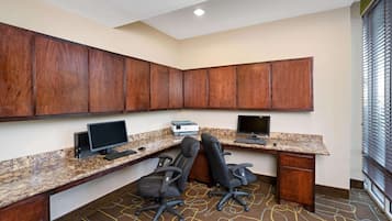 Une salle de conférence équipée de deux bureaux, de deux chaises, d’une grande armoire en bois et d’une imprimante.