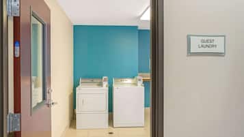 Een wasserette met twee wasmachines en een bordje met de tekst 'GUEST LAUNDRY'.