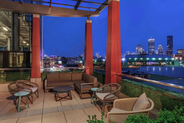 An outdoor seating area with a city skyline view at dusk.