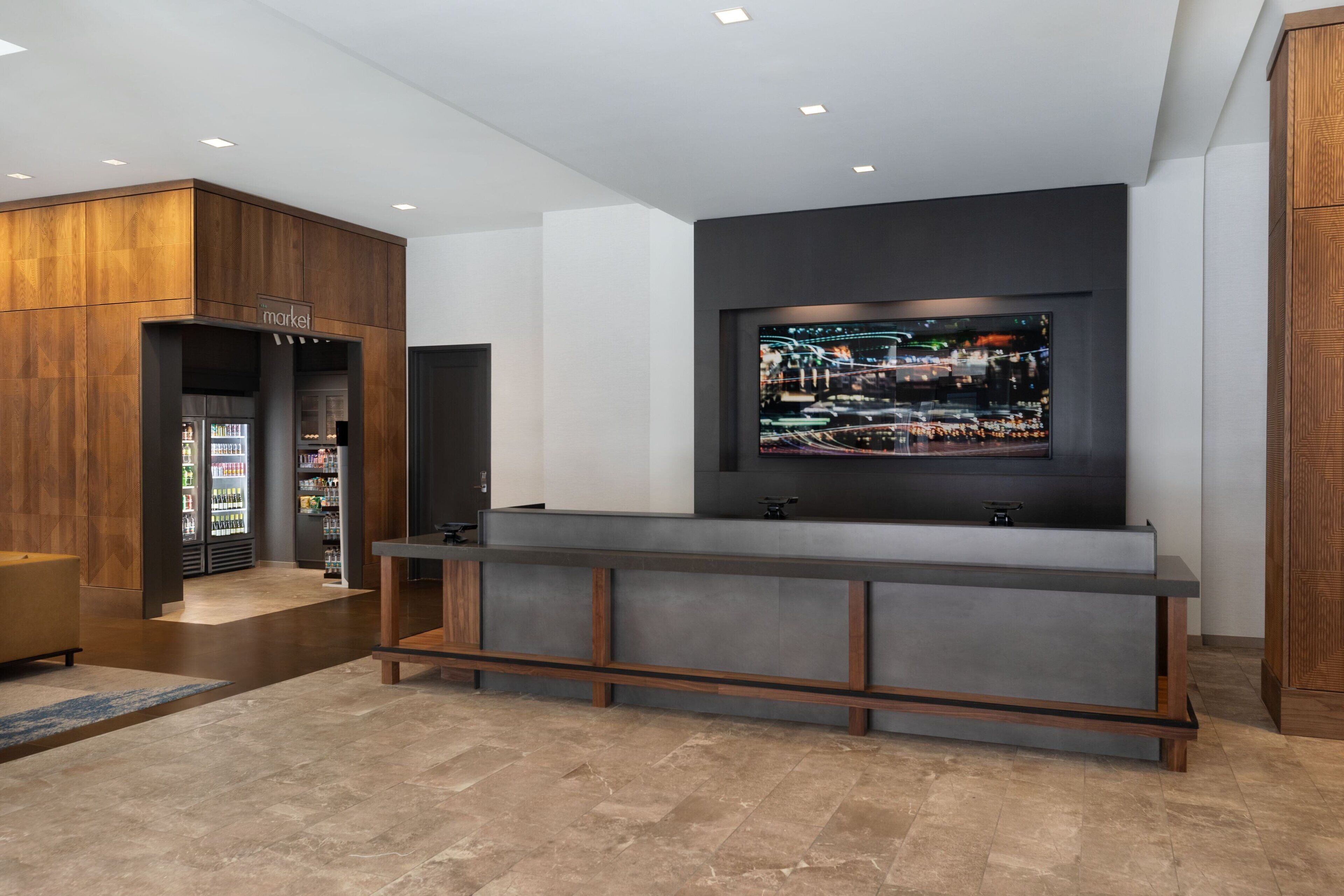 Un área de bar moderna con una pantalla grande, un refrigerador y una máquina expendedora.