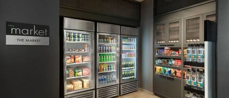 A refrigerated display area with various beverages and snacks, a sign reading "The Market", and a tiled floor.