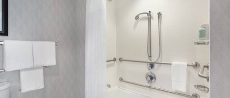 A modern bathroom with a shower, grab bars, and a toilet.