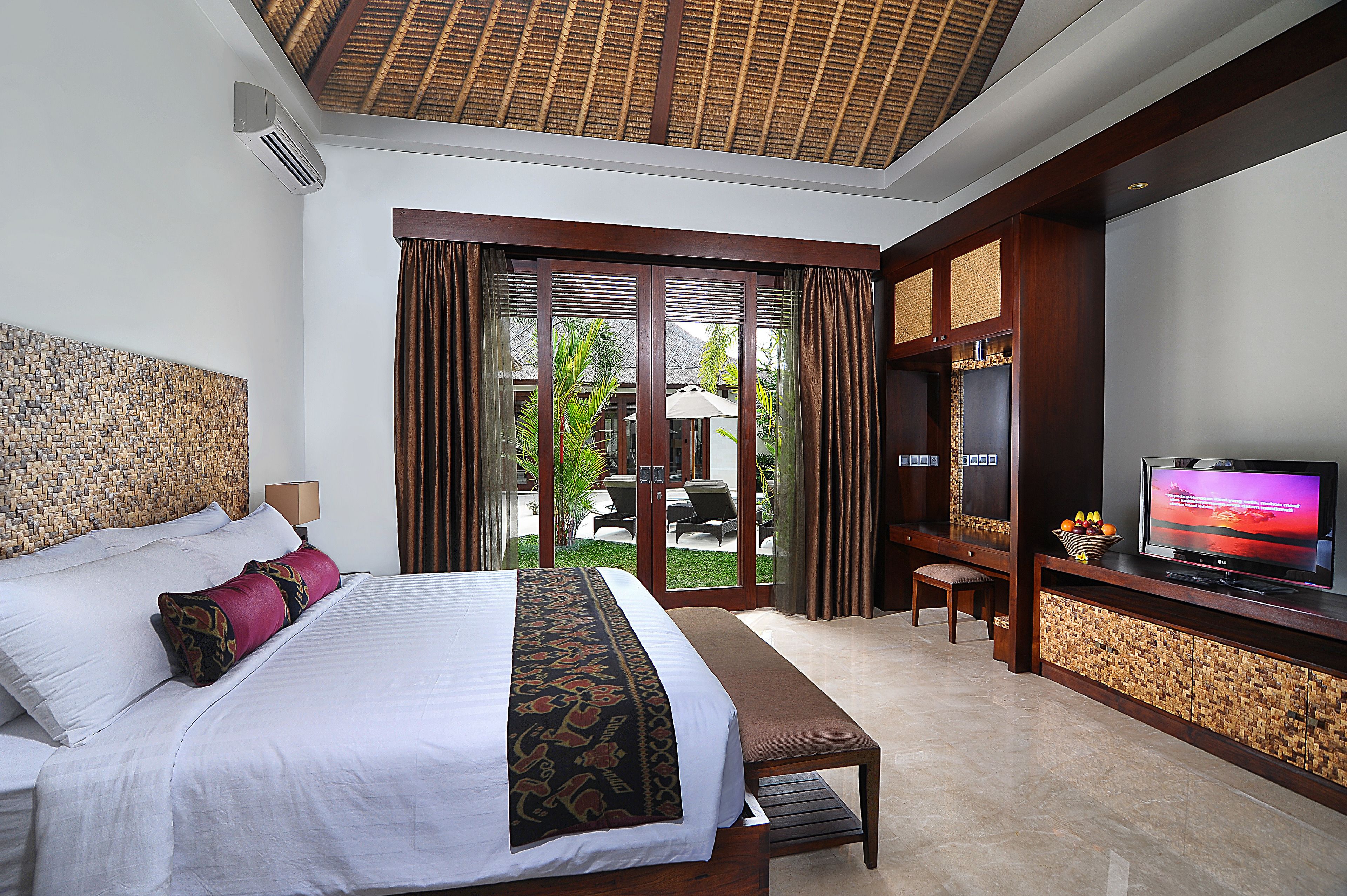 A hotel room with a large bed, a television, and a view of the outdoors.