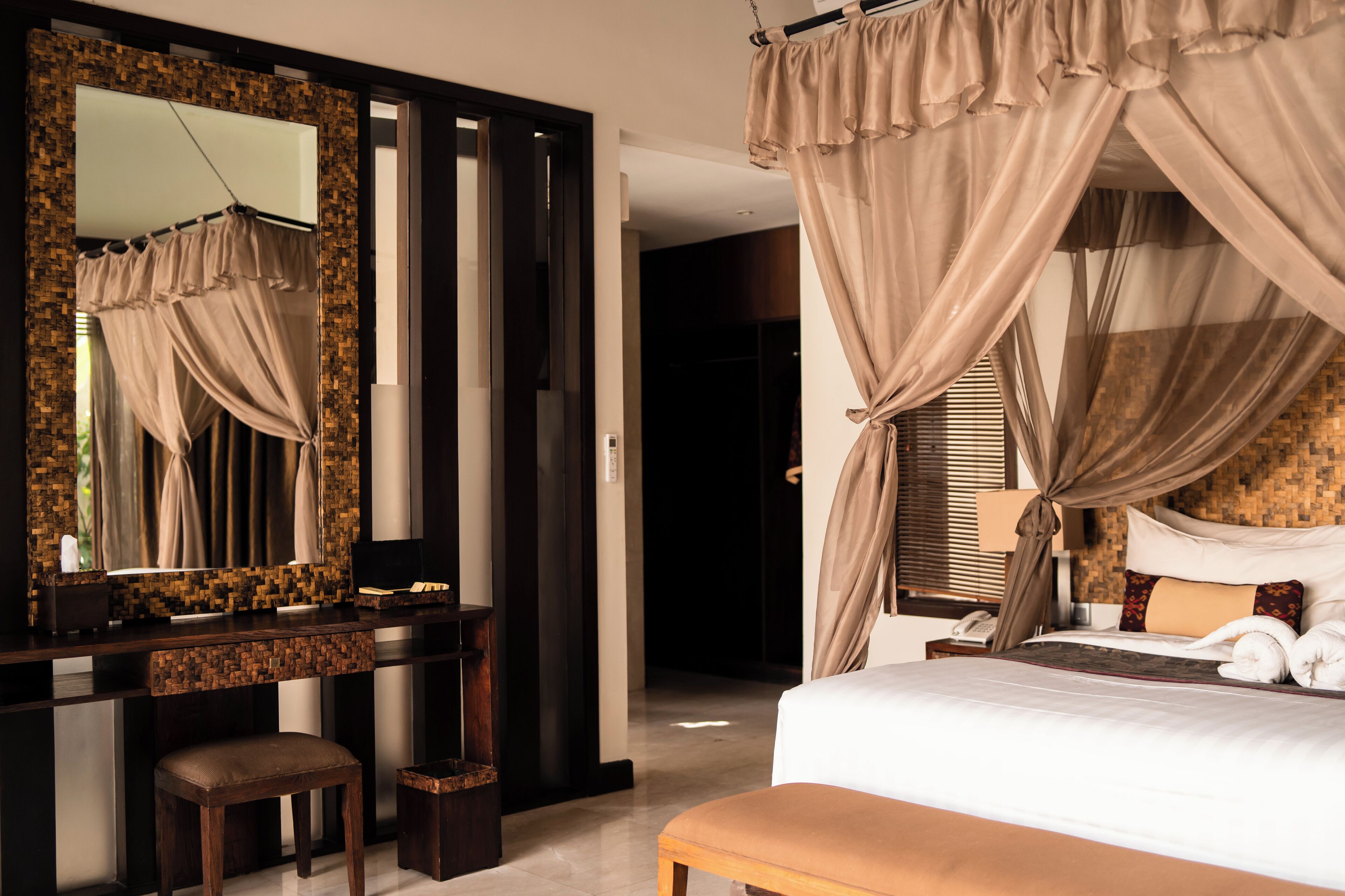 A bedroom with a large bed, a wooden nightstand, a mirror, and a desk with a chair.