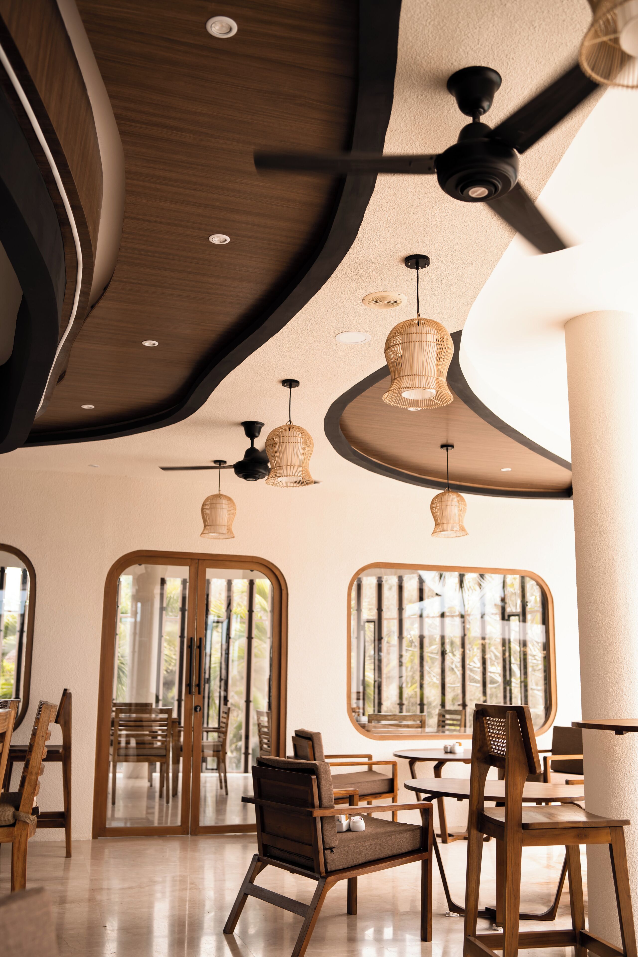 A modern interior with wooden furniture, ceiling fans, and pendant lights.