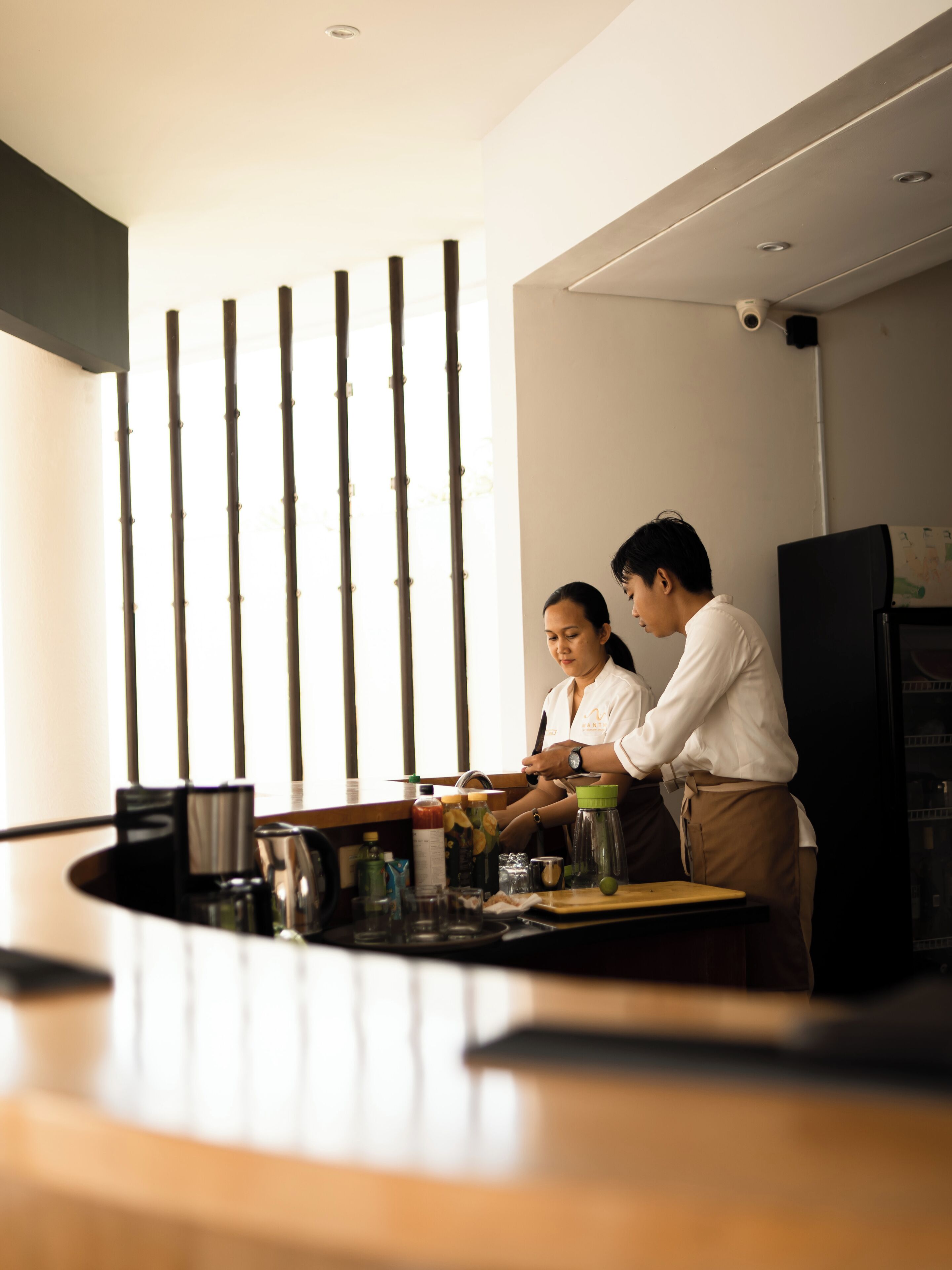 A kitchen area with a counter, a refrigerator, and a bamboo screen in the background.