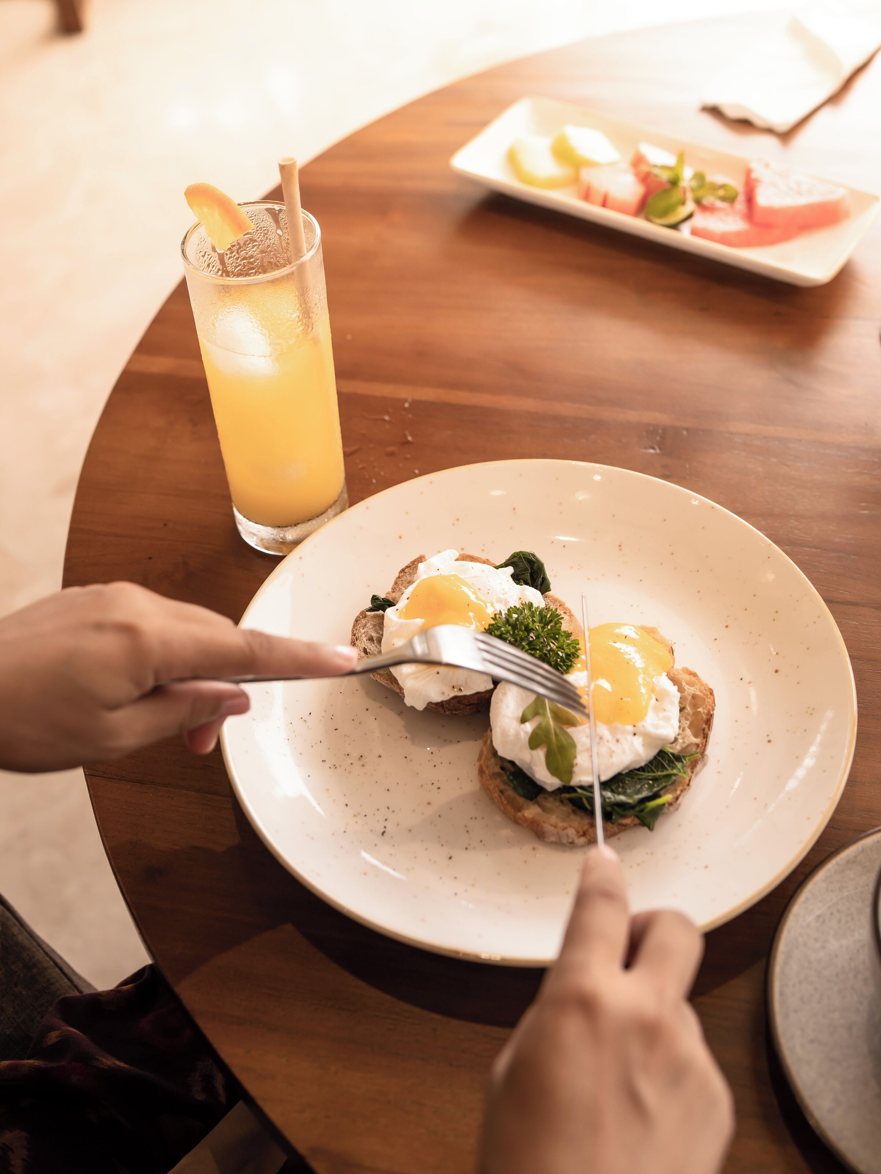 Ein Esstisch mit einem Teller Eggs Benedict und einem Glas Orangensaft.