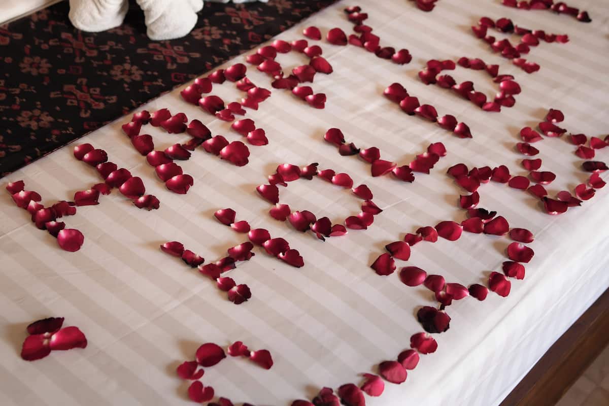 Una cama con pétalos de rosa dispuestos en forma de corazón.