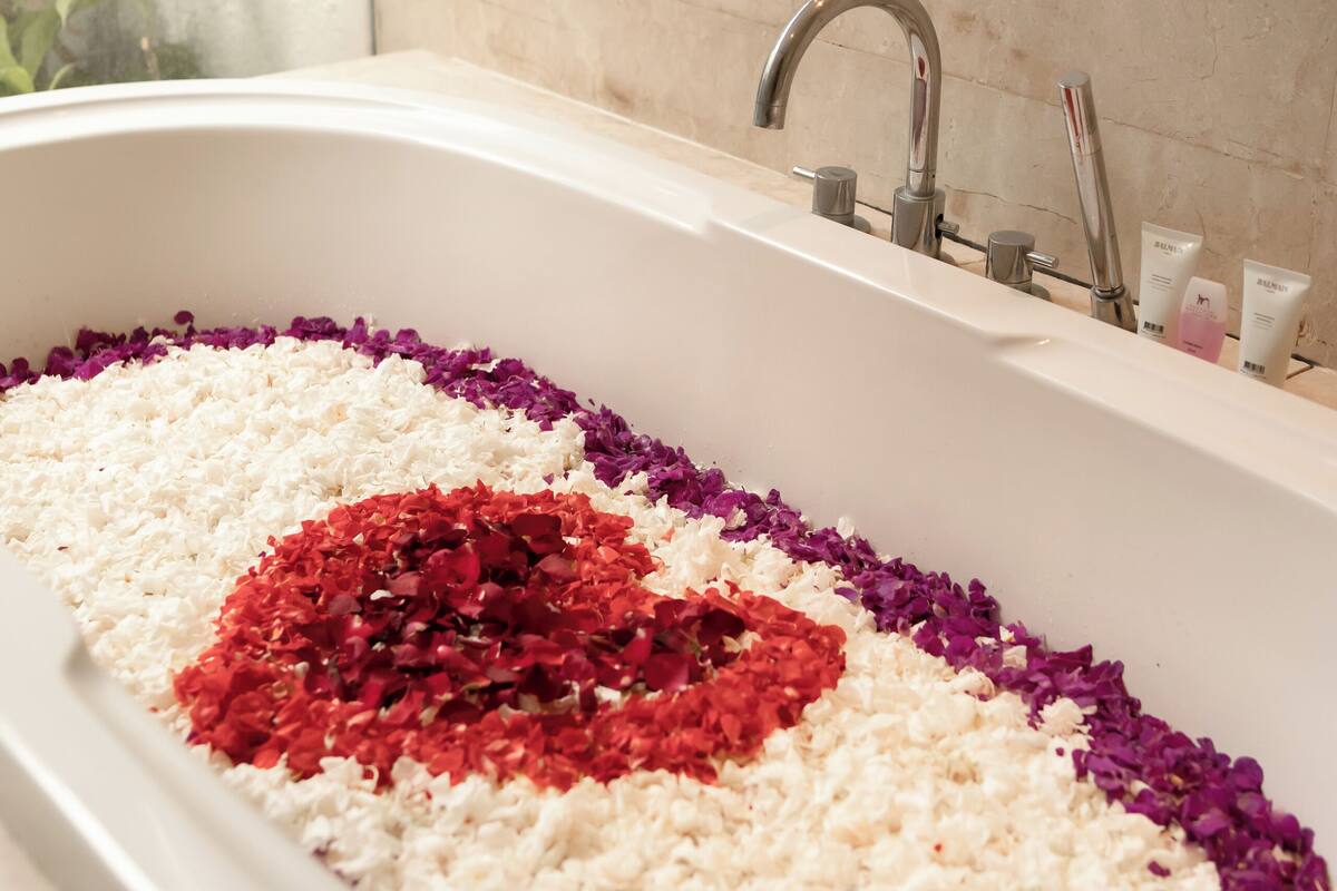 Una bañera llena de arroz y pétalos de flores dispuestos en forma de corazón.