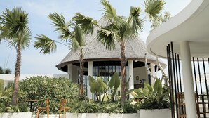 Un bâtiment moderne doté d’une structure de toit circulaire, entouré de palmiers et d’une végétation luxuriante.