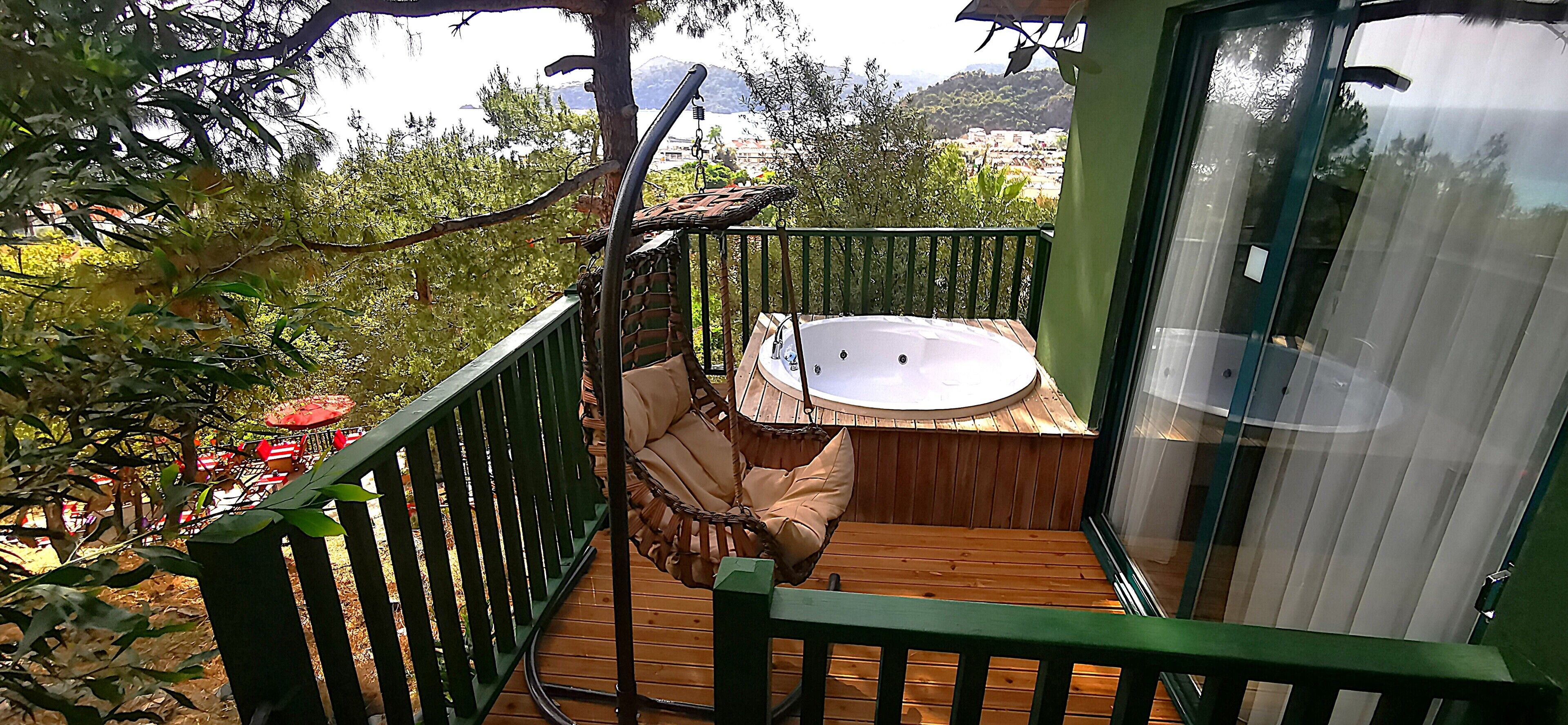 Ein Balkon mit Holzterrasse, einer Hängematte und einer eingebauten Whirlpool-Badewanne.
