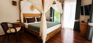 A bedroom with a four-poster bed, a wooden nightstand, a wicker chair, and a television on the wall.