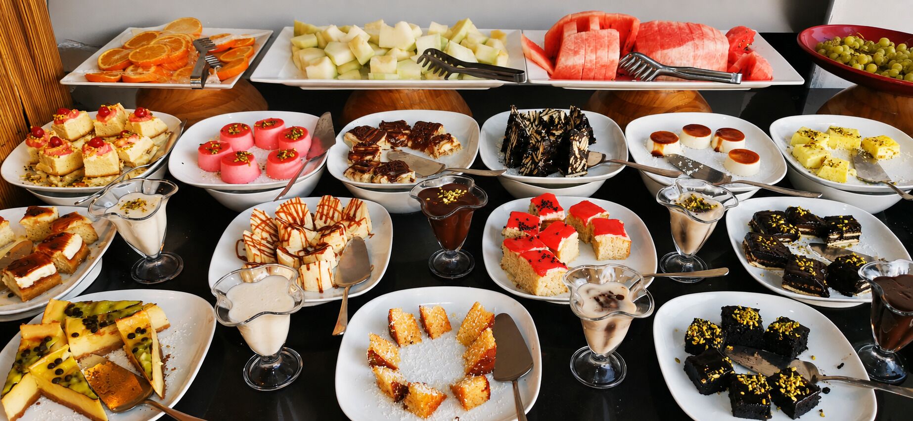 A buffet table with various food items and desserts.