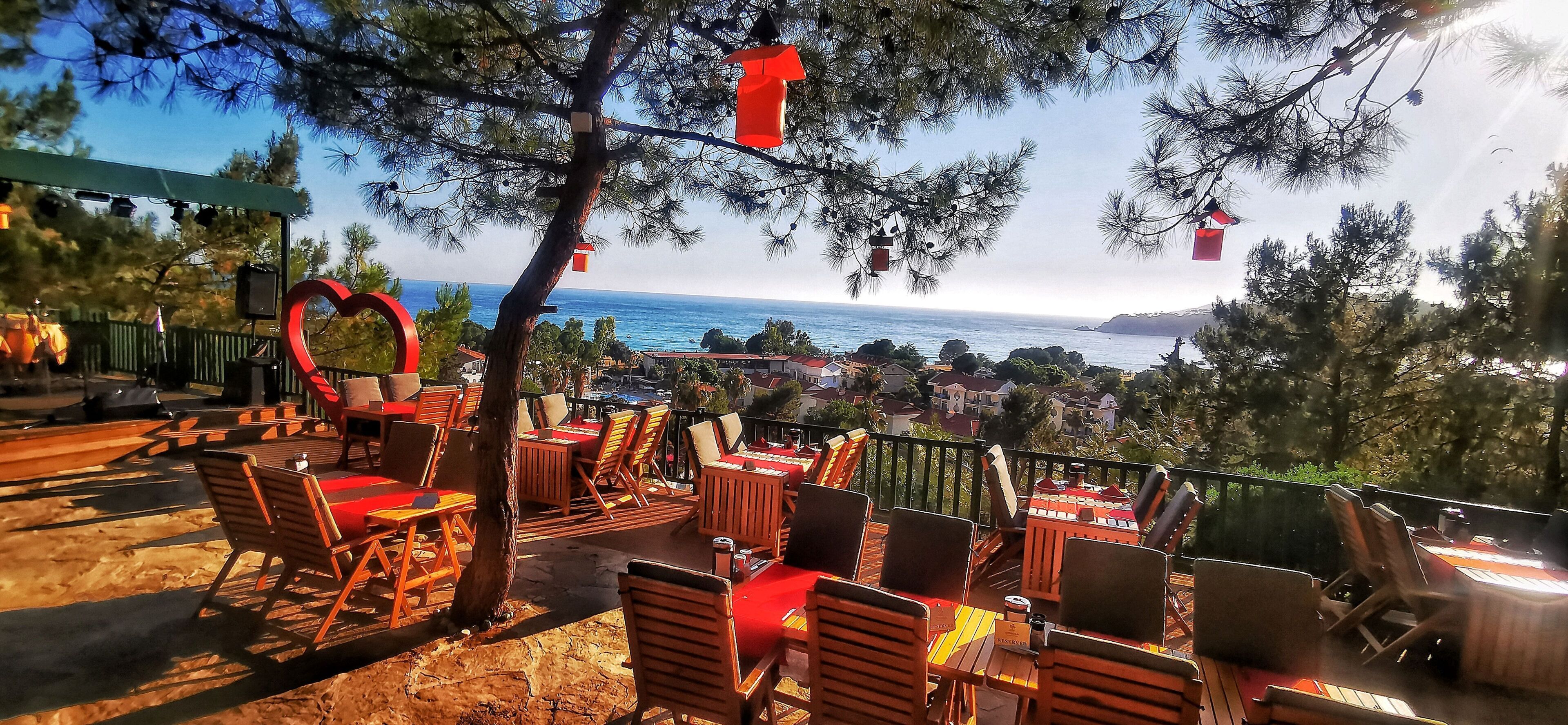 Outdoor seating with tables and chairs, a heart-shaped decoration, and a view of the sea.