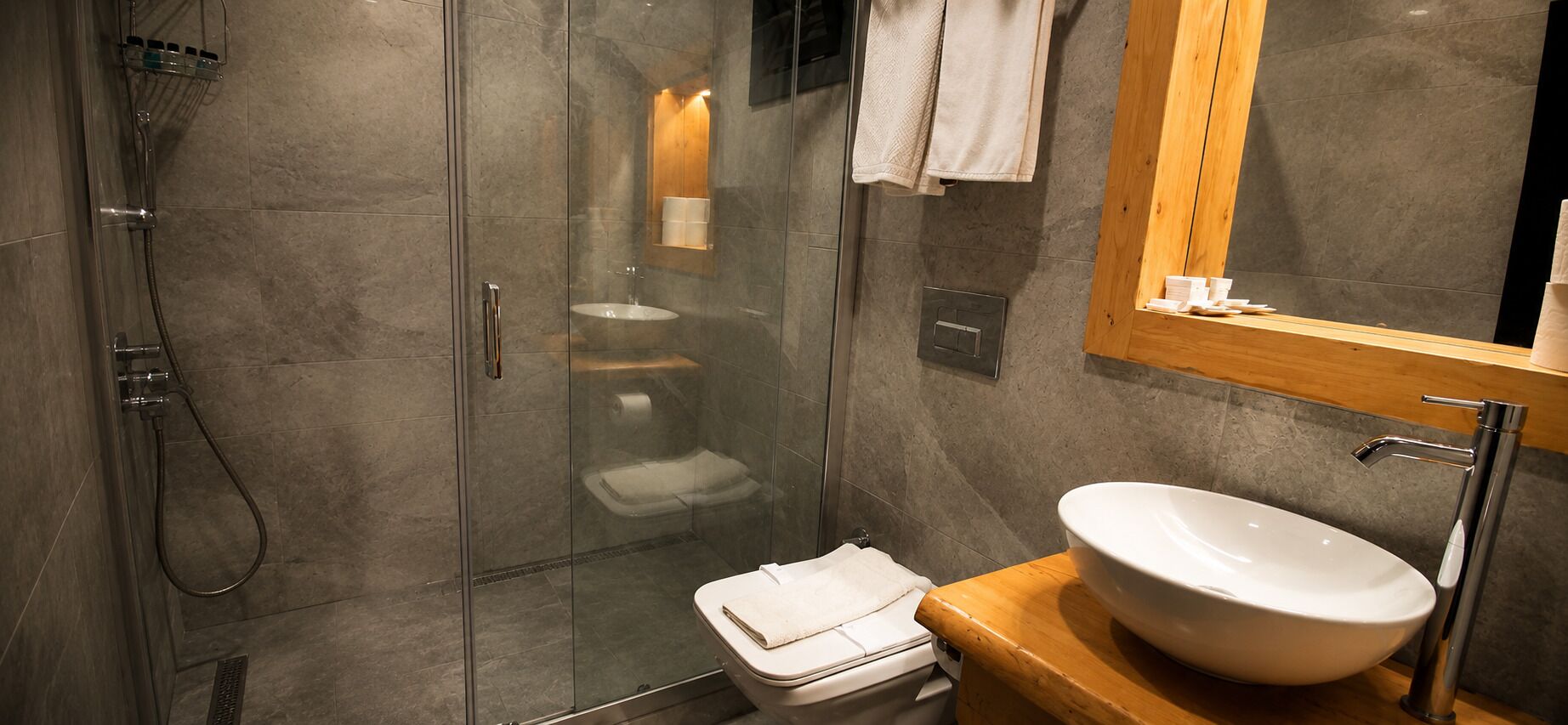 Une salle de bain moderne avec une douche à parois de verre, un lavabo blanc et un meuble-lavabo en bois.