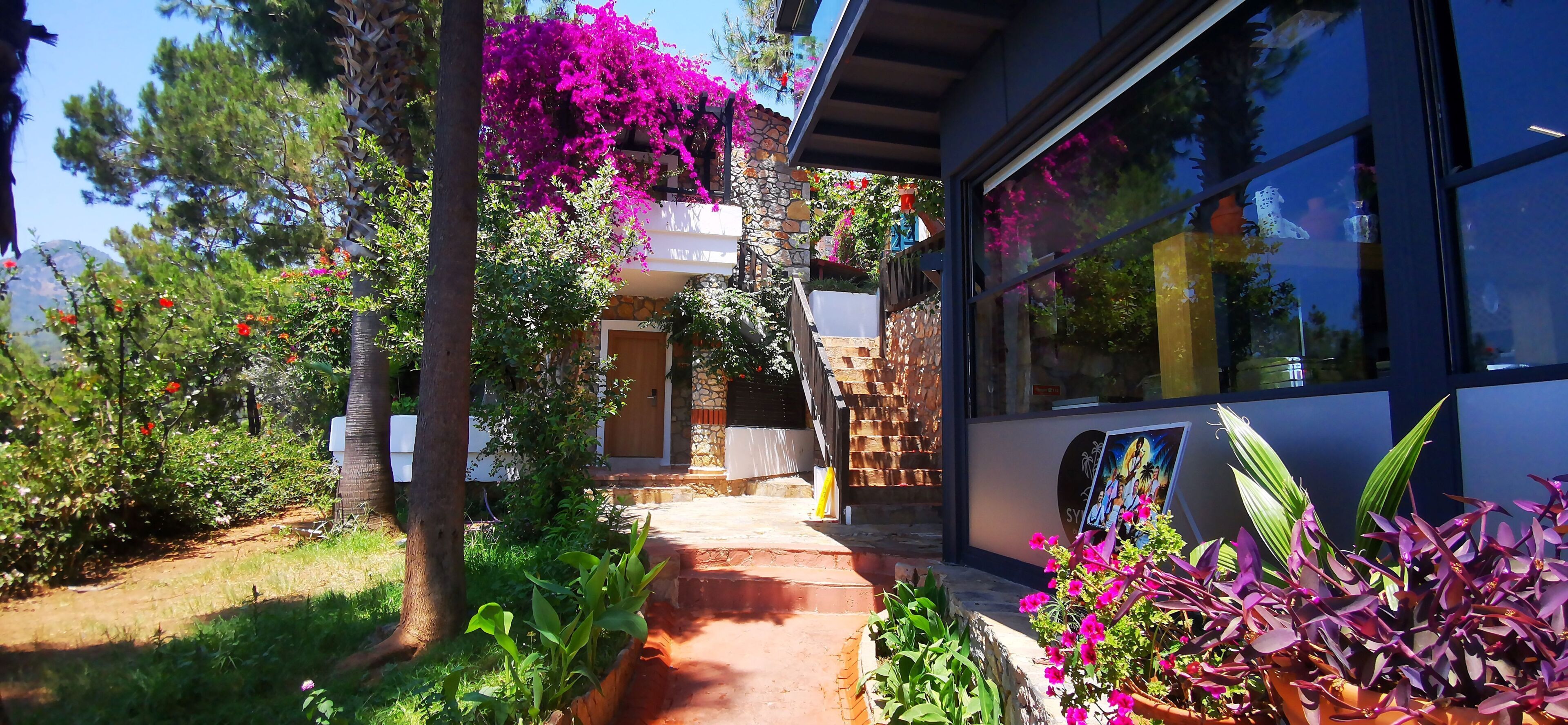 Una casa con facciata in pietra, una porta in legno e un balcone fiorito di fiori viola.
