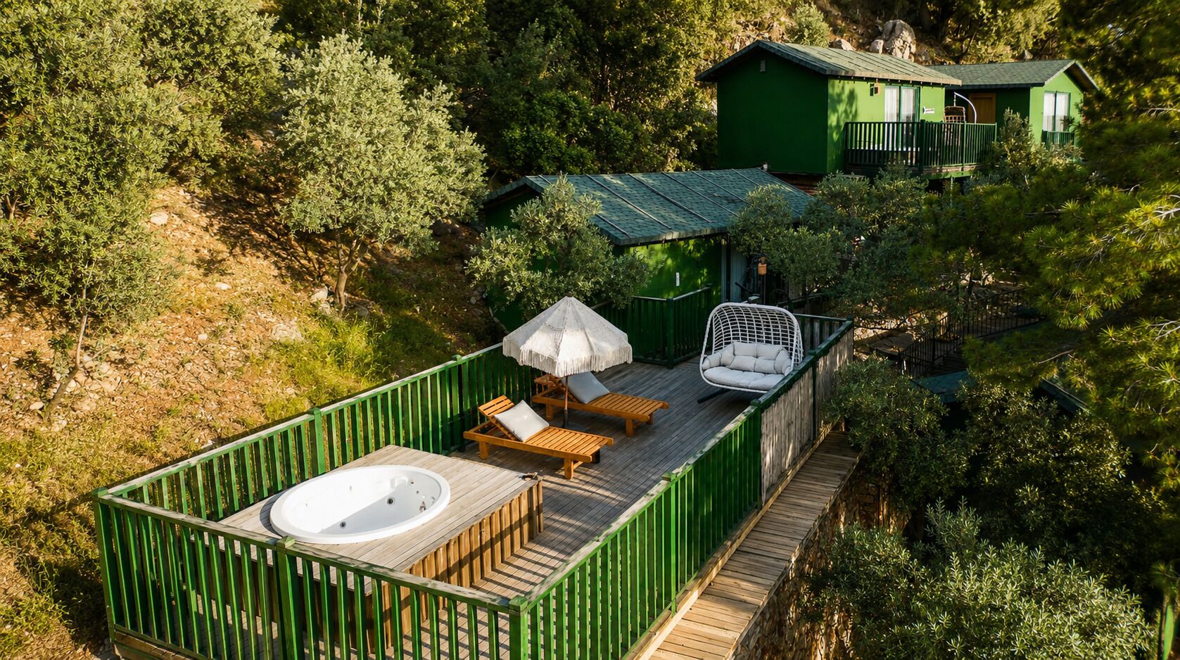 A wooden deck with a hot tub, lounge chairs, and a hanging chair.