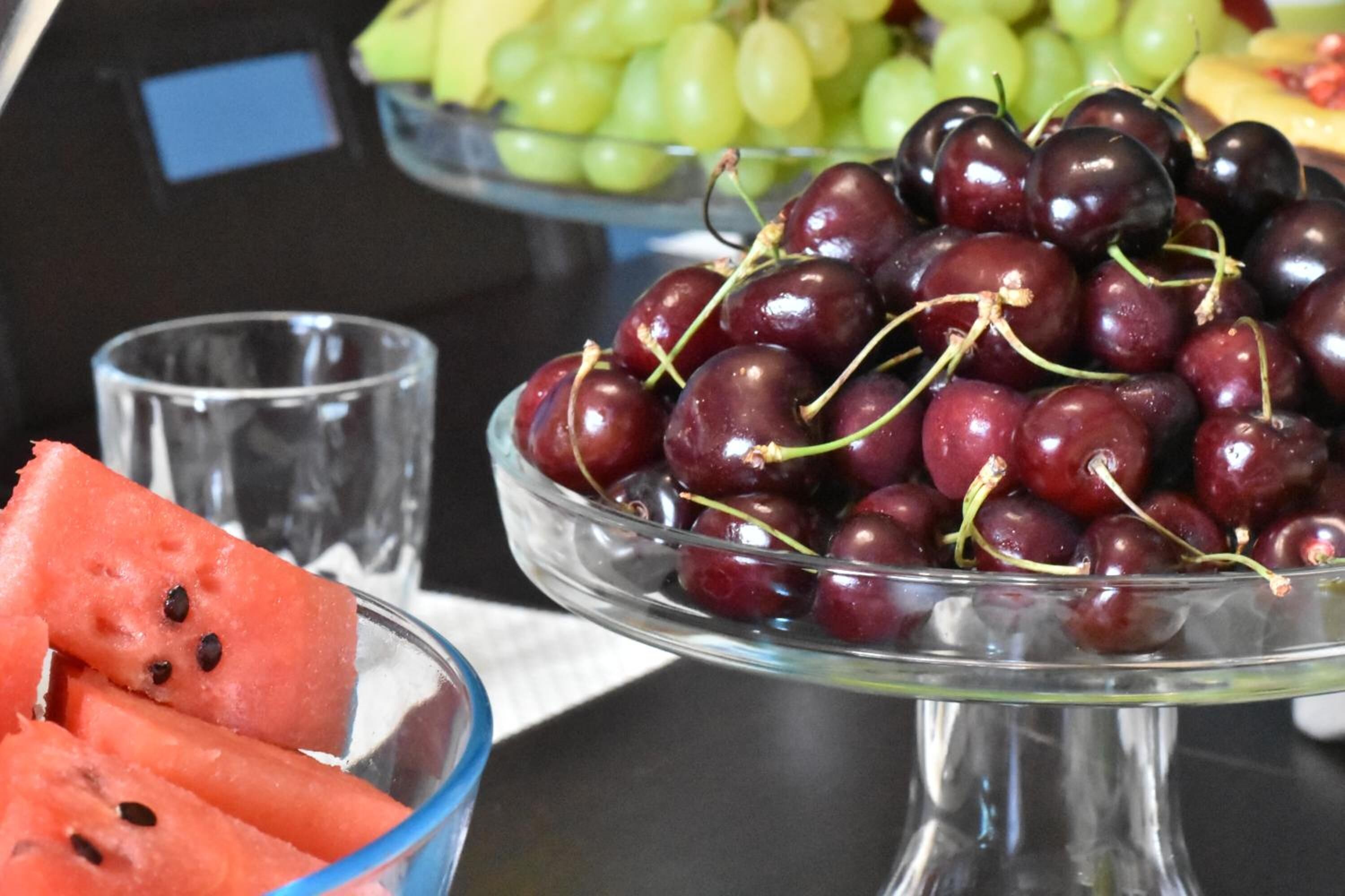 A glass bowl filled with cherries and watermelon slices on a table.