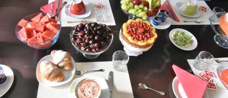 A dining table with various food items, including watermelon, cherries, grapes, and a fruit salad.